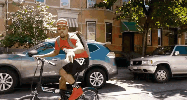 a man wearing a red supreme shirt is riding a bike down a street