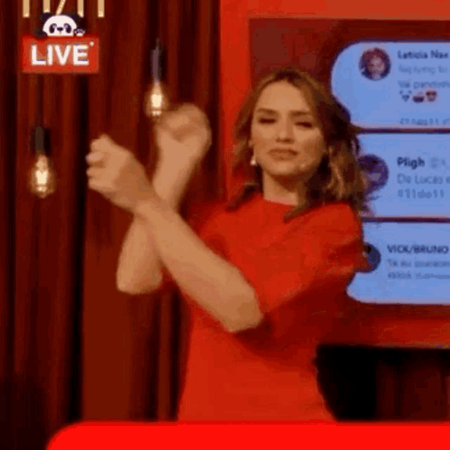 a woman in a red dress is clapping her hands in front of a screen .