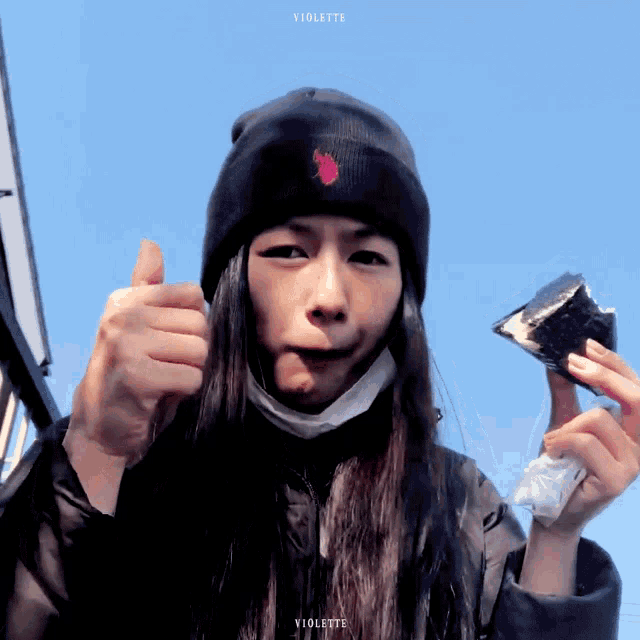 a woman wearing a black beanie with a red flower on it