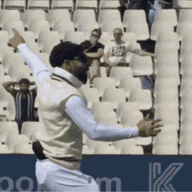 a man in a white vest is throwing a cricket ball
