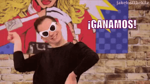 a man wearing sunglasses is standing in front of a poster that says ' ganamos ' on it