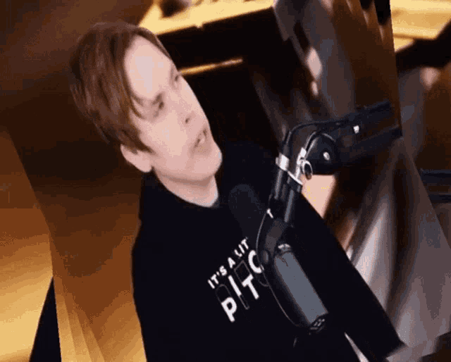 a man wearing a hoodie that says it 's a lit pit stands in front of a microphone