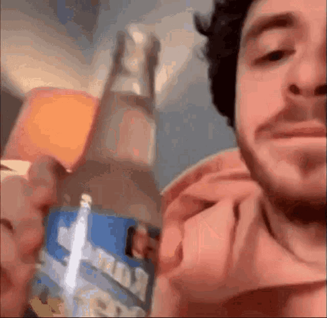 a man is holding a bottle of beer in front of his face
