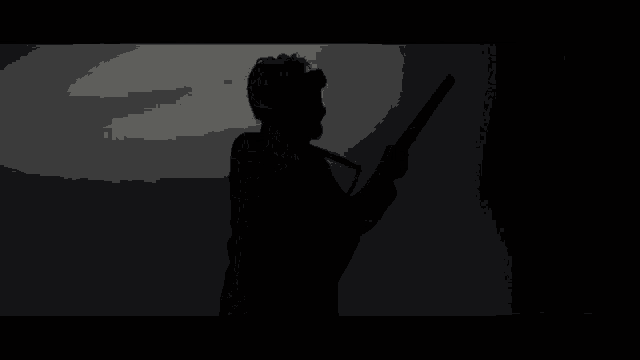 a silhouette of a man holding a guitar in a dark room .