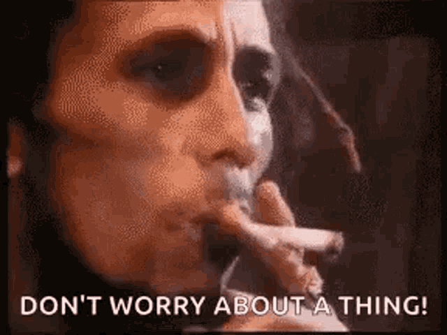 a close up of a person smoking a cigarette and saying `` don 't worry about a thing '' .