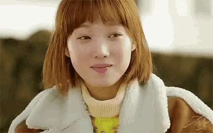 a close up of a woman 's face wearing a fur coat and a sweater .