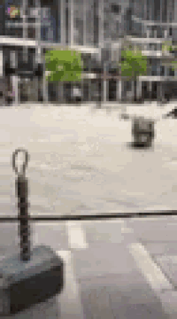 a blurred image of a city street with a fence in the foreground and trees in the background .