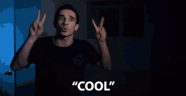 a man in a black shirt giving a peace sign with the word cool behind him