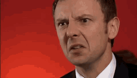 a man in a suit and tie is making a funny face .