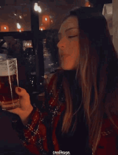 a woman in a plaid jacket is drinking from a plastic cup