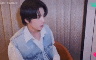 a man is sitting in a chair wearing a white shirt and a blue vest .