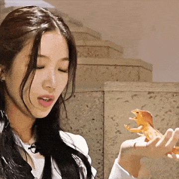 a woman is holding a toy dinosaur in her hand and looking at it .