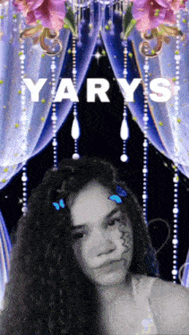 a girl with curly hair is standing in front of a purple curtain with the word yarys on it