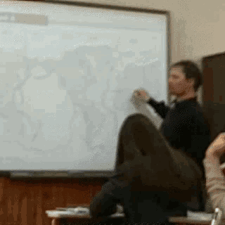 a man is standing in front of a white board with a map on it