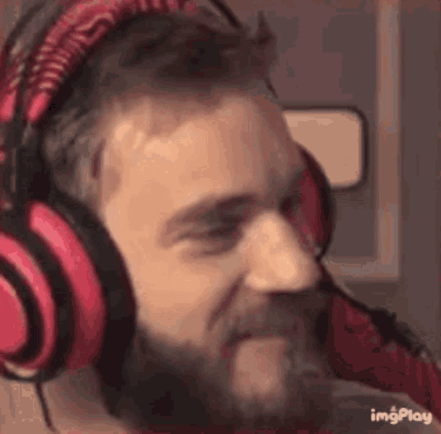 a man with a beard is wearing red headphones and making a funny face .