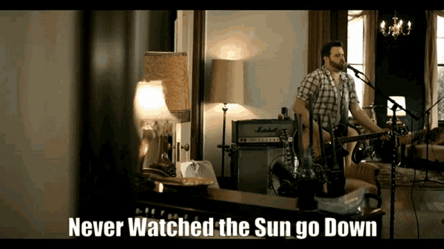 a man singing into a microphone with the words never watched the sun go down above him