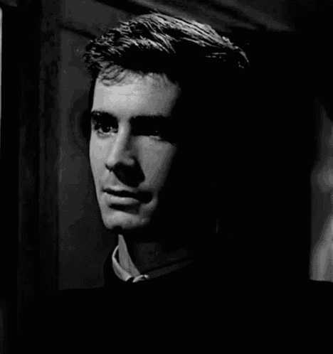 a black and white photo of a smiling man in a dark room .