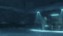 a man in a white suit and hood is standing in a dark room .