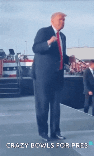 a man in a suit and tie is standing on a stage with the words crazy bowls for pres below him