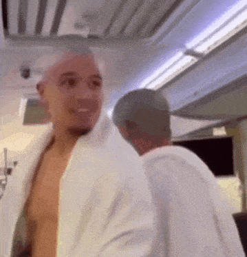 a shirtless man is standing next to another shirtless man in a white robe