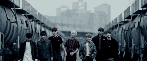 a group of young men are standing next to each other in front of a train .