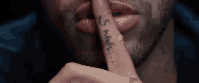 a man with a tattoo on his finger covering his mouth .