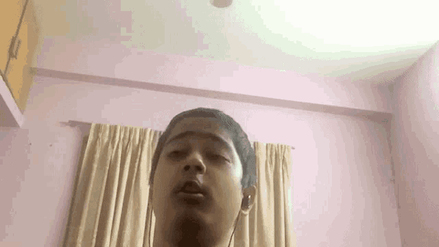 a young man is wearing headphones and making a funny face in a room .