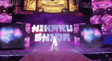 a woman stands on a stage in front of a sign that says hikaru shioa