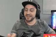 a man wearing headphones and a hat is holding a camera .