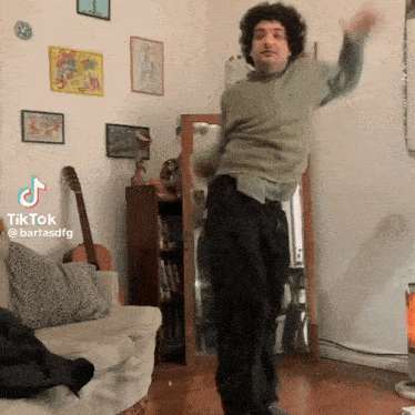 a man is dancing in a living room with a guitar and a mirror