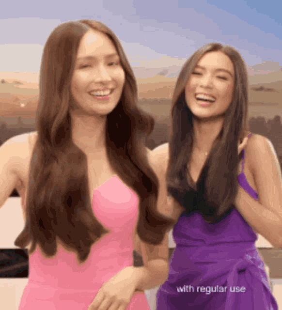 two women in pink and purple dresses are standing next to each other smiling