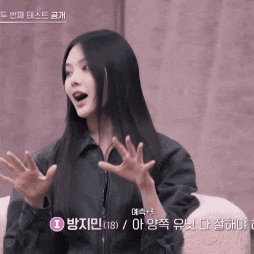 a woman with long black hair is sitting on a couch with her hands outstretched in front of a sign that says i
