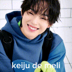 a close up of a person wearing a blue hoodie and smiling with the words keiju de meli on the bottom .