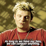 a man wearing a red shirt with the words " as long as we have our fans we can conquer anything "