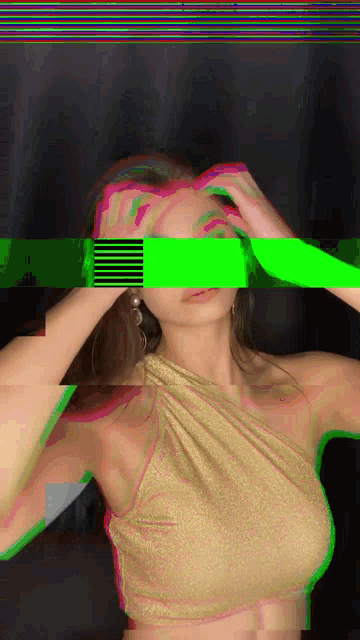 a woman in a gold top covering her eyes with a green stripe