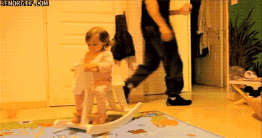 a little girl is riding a rocking horse while a man walks behind her ..