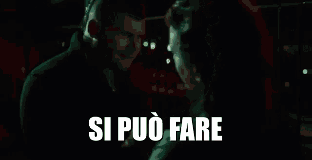 a man and a woman are standing next to each other in a dark room and the words si può fare are written in white letters