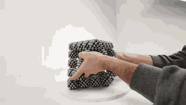 a person is holding a triangle made out of metal balls