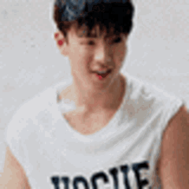 a young man wearing a white sleeveless t-shirt with the word vogue on it .