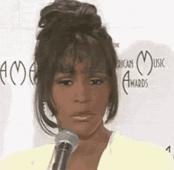 a woman is talking into a microphone and making a face .