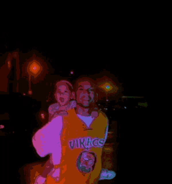 a man in a vikings jersey is carrying a little girl