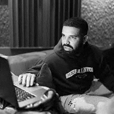 a black and white photo of drake sitting on a couch with a laptop .