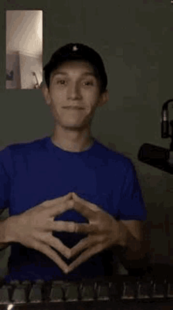 a young man wearing a blue shirt and a black hat is making a funny face .