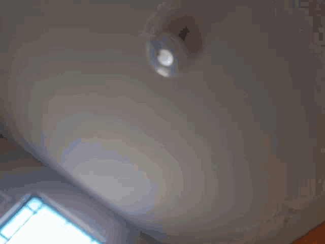 a white wall with a light on it and a window behind it