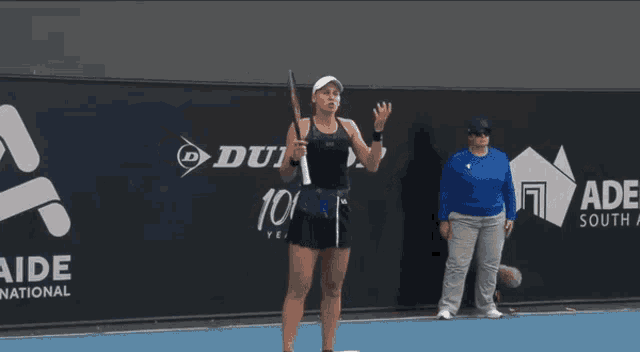 a woman holding a tennis racquet on a tennis court with a dunlop logo in the background