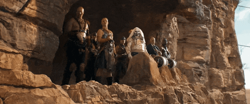 a group of people are standing on top of a rock formation