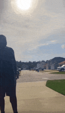 a man is walking down a sidewalk in a residential area