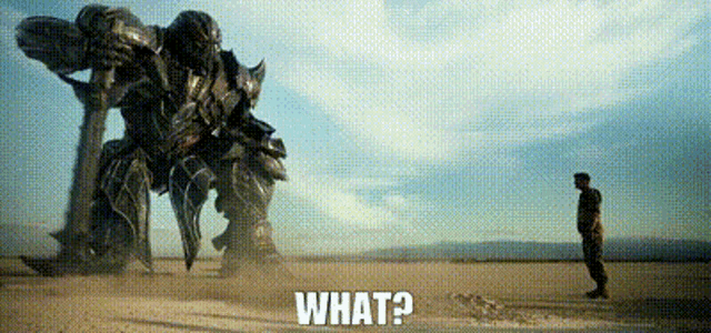 a man is standing in the middle of a desert in front of a large robot .