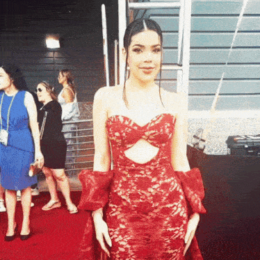 a woman in a red lace dress is posing for a picture on a red carpet