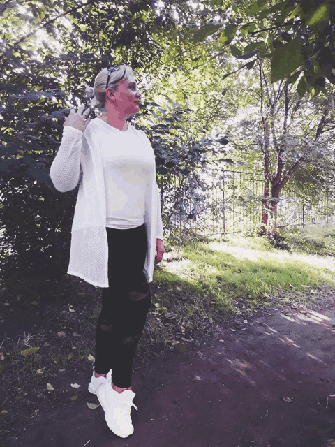 a woman wearing a white cardigan and black pants